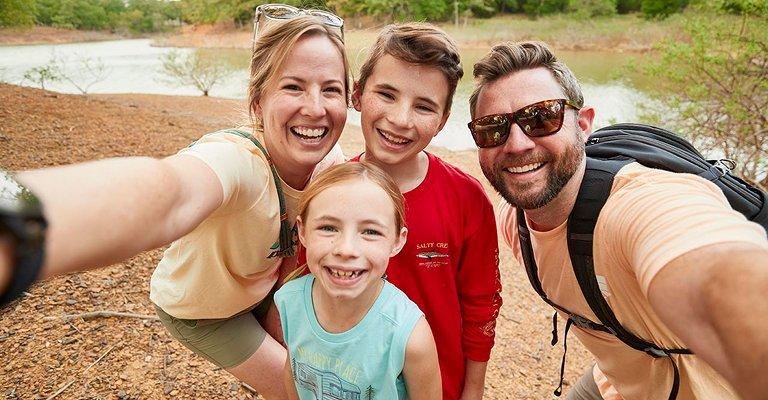 Child rides bike next to her father riding a skateboard